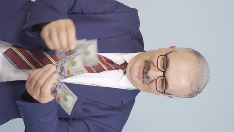 vertical video of old businessman counting money looking at camera.