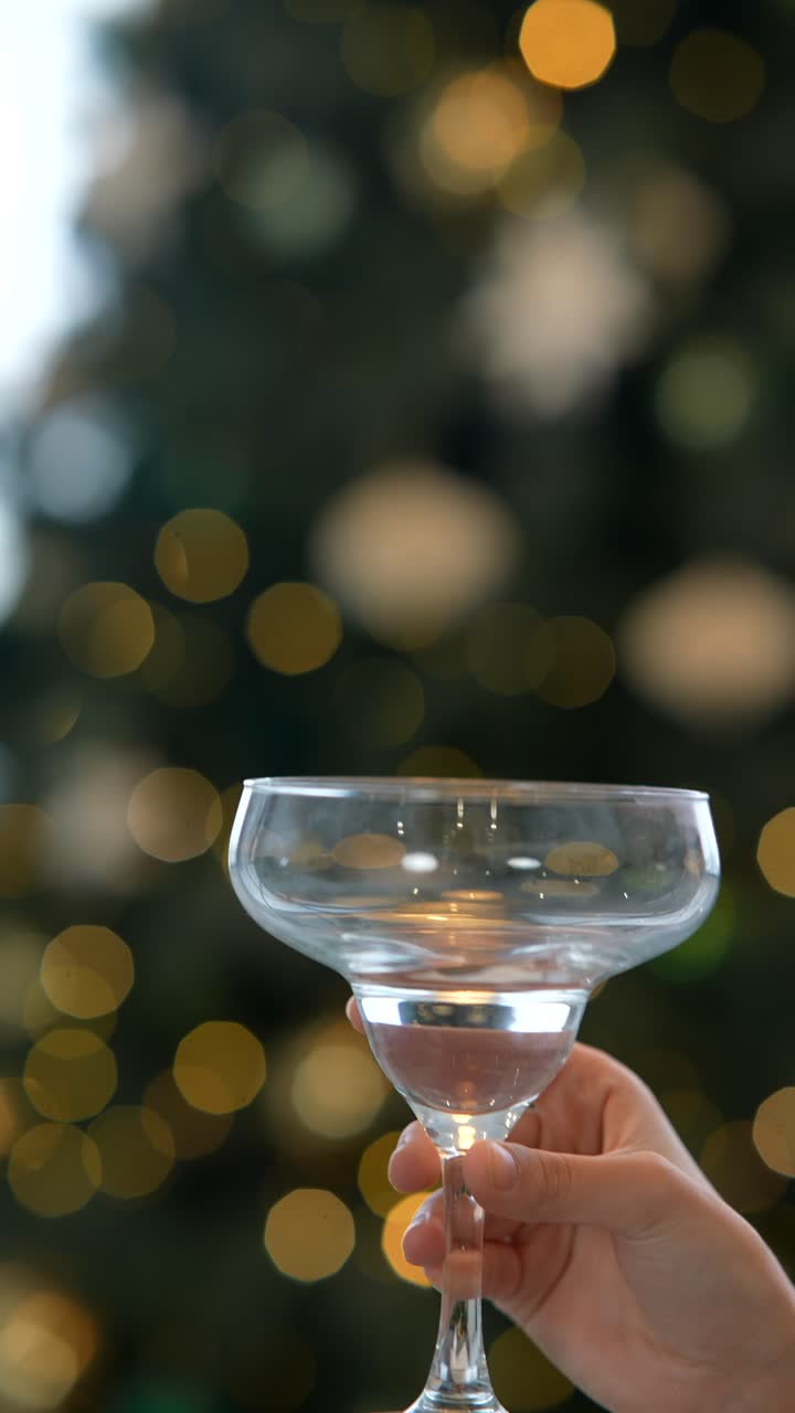 크리스마스 트리 앞에 마가리타 글래스를 들고 있는 손