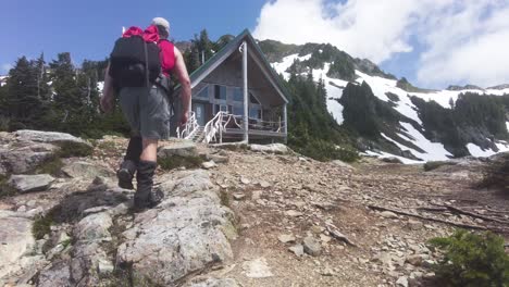 hiker walking toward a mountain hut on mount 5040, vancouver island, canada