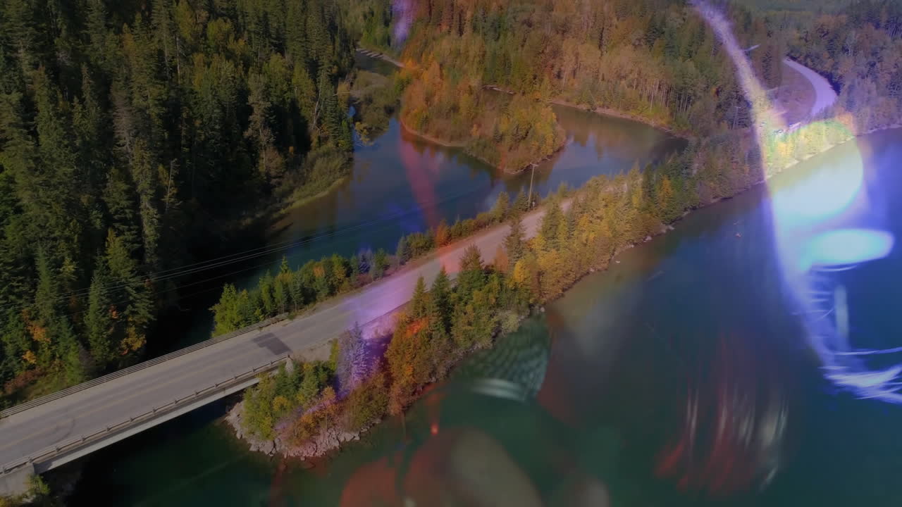 hand capturing winding road and bridge over lake via lens overlay, showcasing technology