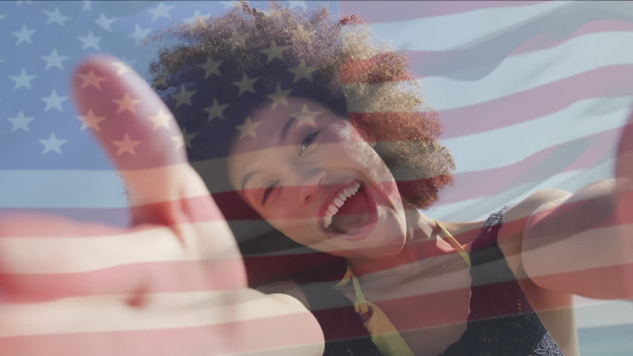 Animation of flag of united states of america over happy african american woman on beach
