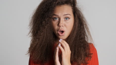 caucasian curly haired woman looking scared at the camera.