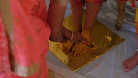 appliquer de la pâte de curcuma haldi sur les pieds de la mariée lors d'une cérémonie hindoue - en gros plan