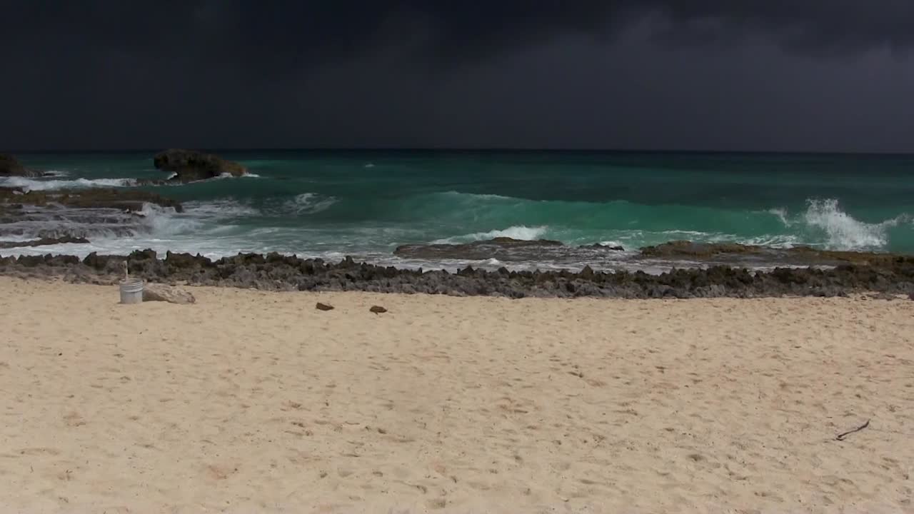 불길 한 폭풍 이 다가오고, 먼 곳 에서 비 가 내리는 모습 을 모래 해변 에서 볼 수 있다