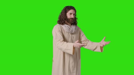 studio shot of man wearing robes with long hair and beard representing figure of jesus christ preaching on green screen