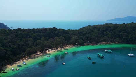 koh wai bay beach with boats anchored in turquoise waters. majestic aerial view flight pull in drone