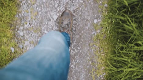 man in blue jeans hiking-walking on stony path in slow motion - top down view from waist