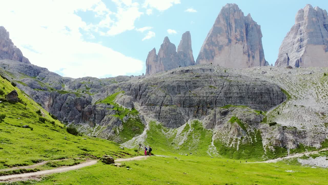 Alpine landscape with hikers moving under dramatic cliffs in Italian Dolomites