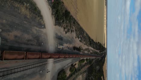 un largo tren de carga con vagones de hierro que pasa por el área de esperance, australia occidental