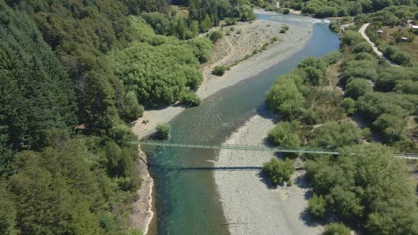 arial high angle of rio azul river and enervated bridge between pine tree woods, patagonia argentina