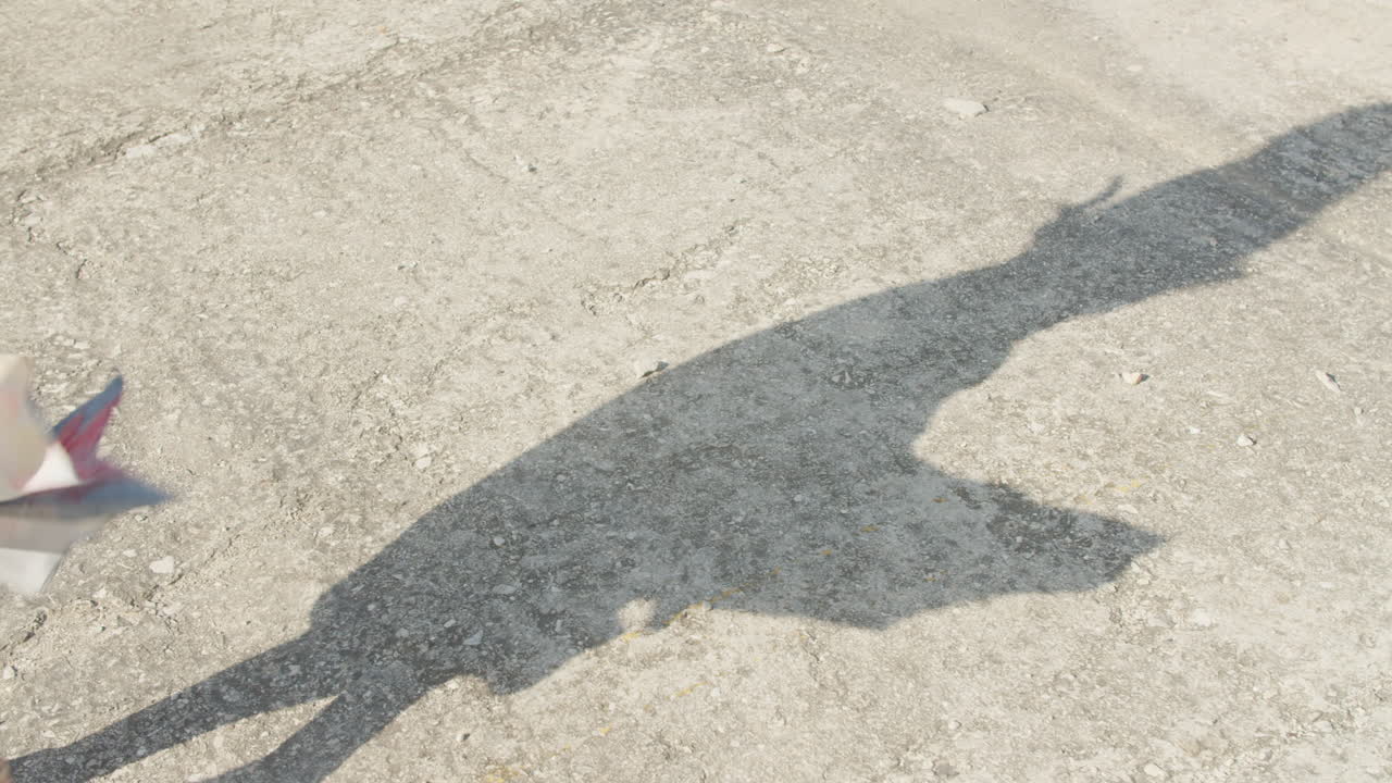 High quality video of a long shadow moving across a sunlit Havana street, capturing rough pavement textures and warm Caribbean light