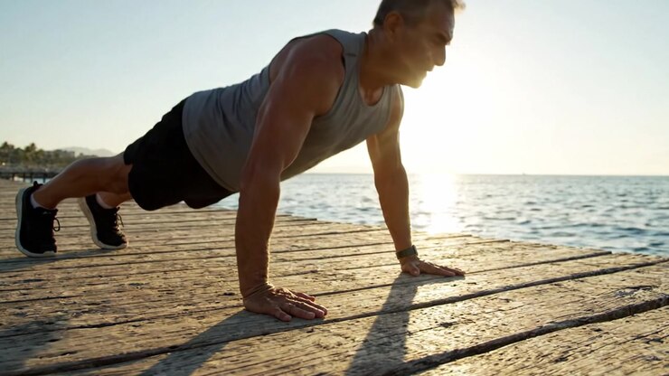 A Dedicated Individual Engages in a Morning Push-Up Workout on a Scenic Wooden Pier with a Beautiful Sunrise Over Glimmering Water in the Background