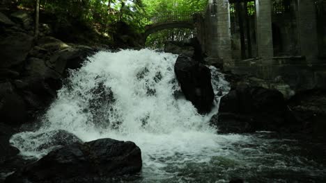 caída de agua rugiendo a través de las ruinas de un antiguo molino en medio del parque provincial de gatineau en quebec