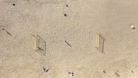 aerial: symmetrical descend shot of football court on a sandy beach on sunny day