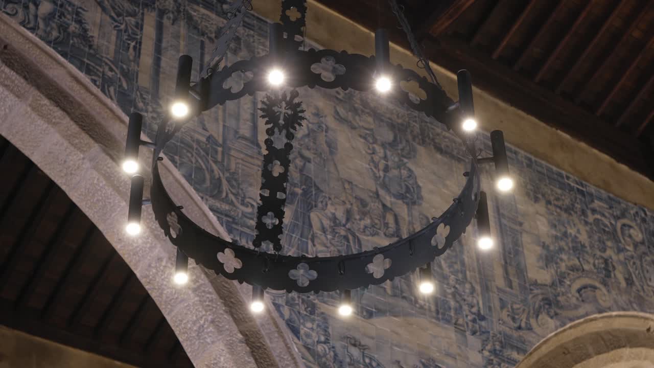 metal chandelier lit under traditional blue tile mural in church
