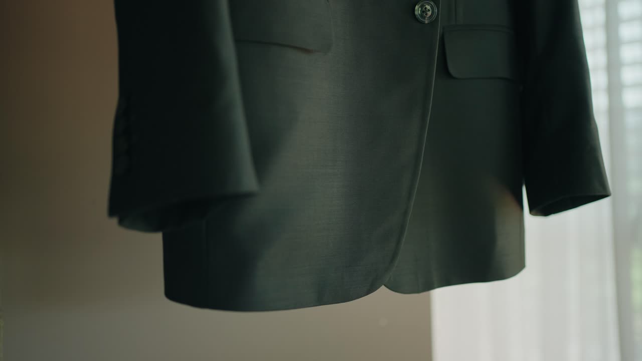 Detail of a dark formal suit jacket hanging, ready for a special event or wedding preparation