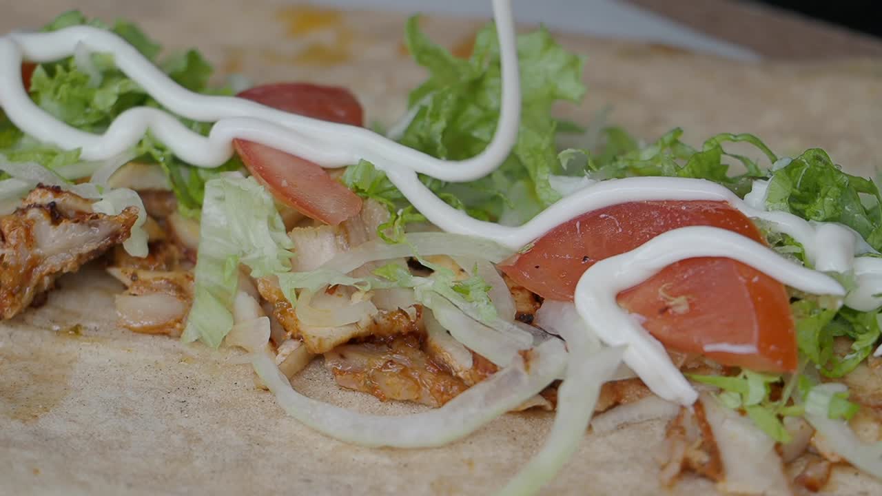 Versare salsa bianca a filo su un delizioso involtino di kebab di pollo