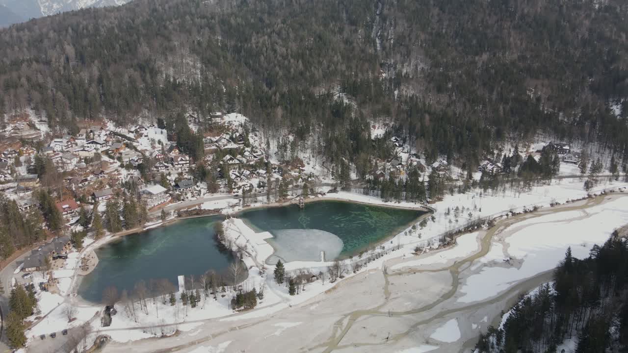 lago alpino en invierno cubierto de nieve y bosque en segundo plano.