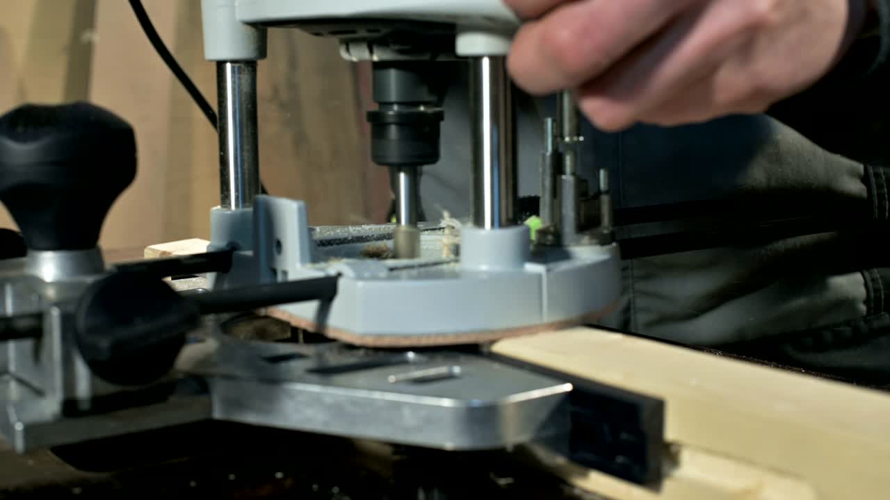 primer plano de la mano de un carpintero trabajando con un cortador eléctrico manual en un taller casero.