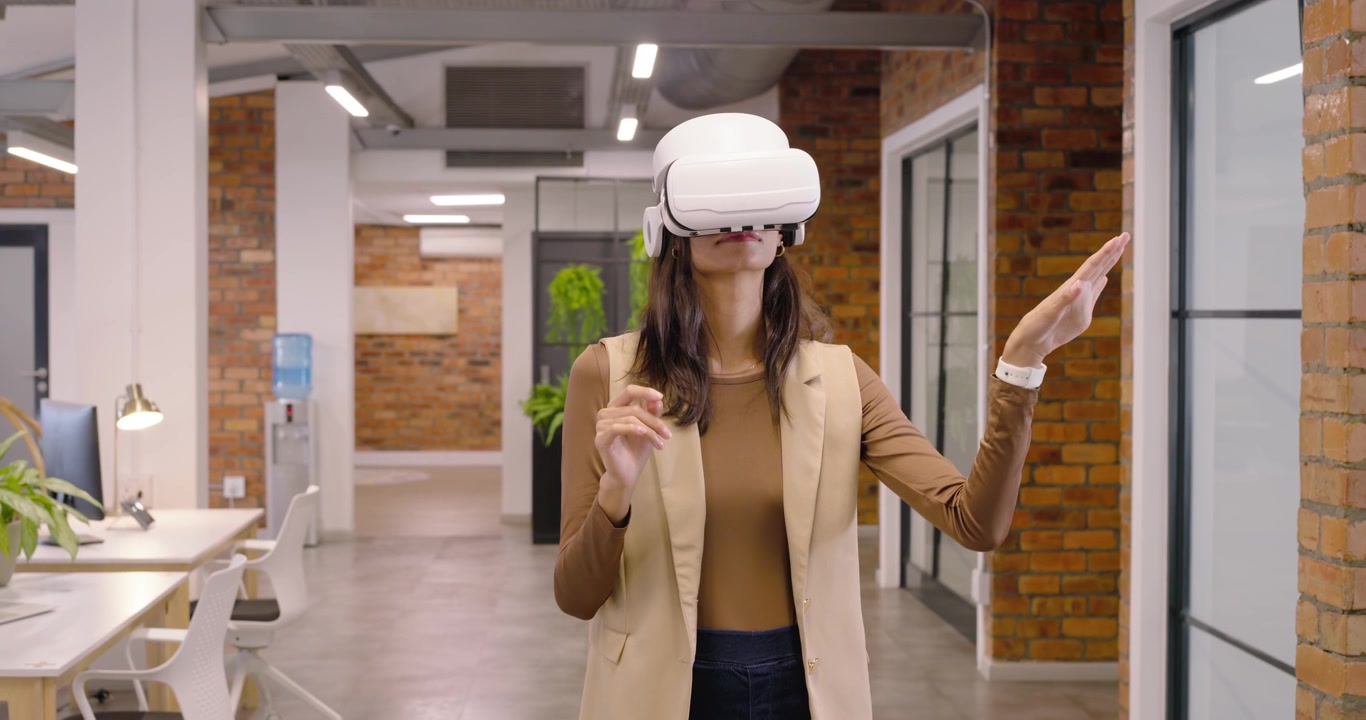 Afroameričanka reagující na výzvu ve VR, ťukající na headset a kontrolující hodinky v kanceláři.