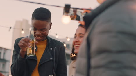 happy multi ethnic friends enjoying weekend rooftop party drinking alcohol posing for photo  young man using smartphone sharing celebration on social media