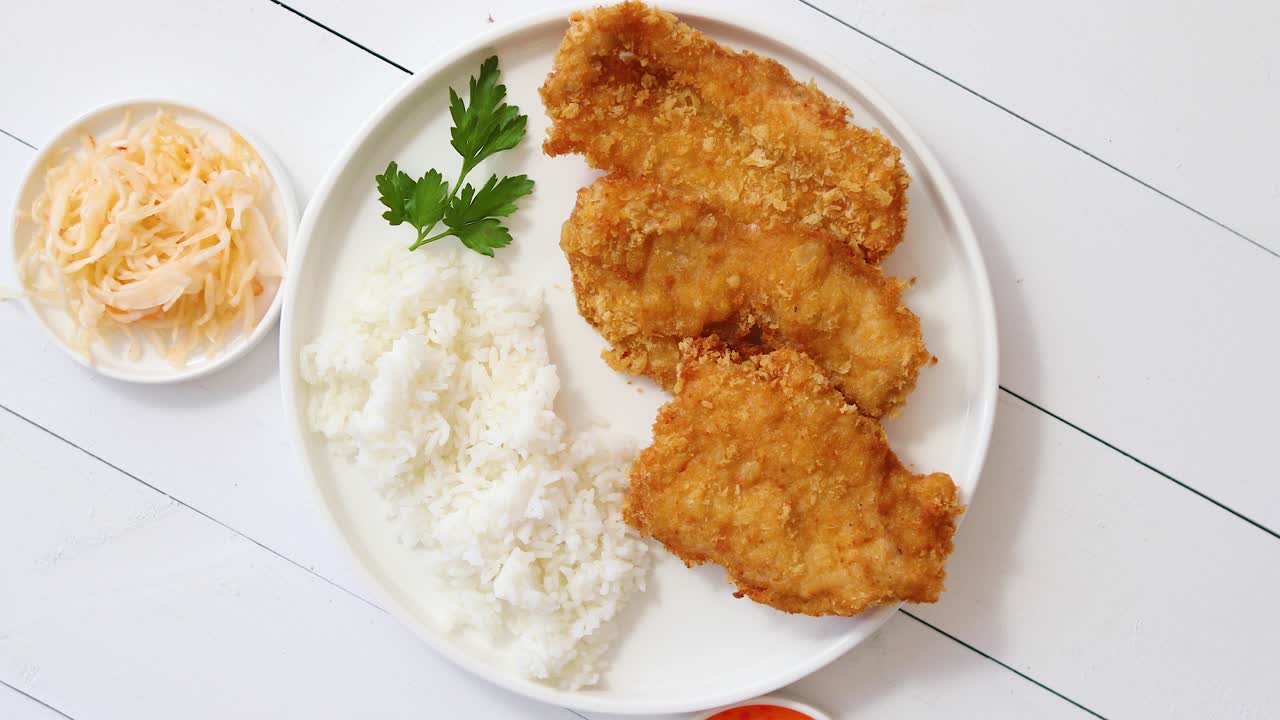 빵가루에 튀긴 바삭한 치킨은 흰색 나무 배경 위에 있는 쌀 전망과 함께 제공됩니다.