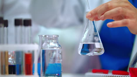 chemical reaction in lab flask. chemist hands doing chemical experiment in flask