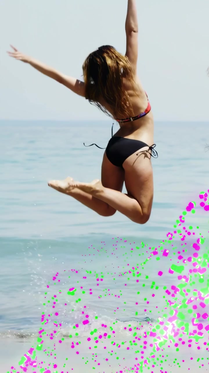 Video verticale: Donna in viaggio che cammina nella risacca, salta le onde, gioca, guada e si ferma, con punti rosa sulle gambe