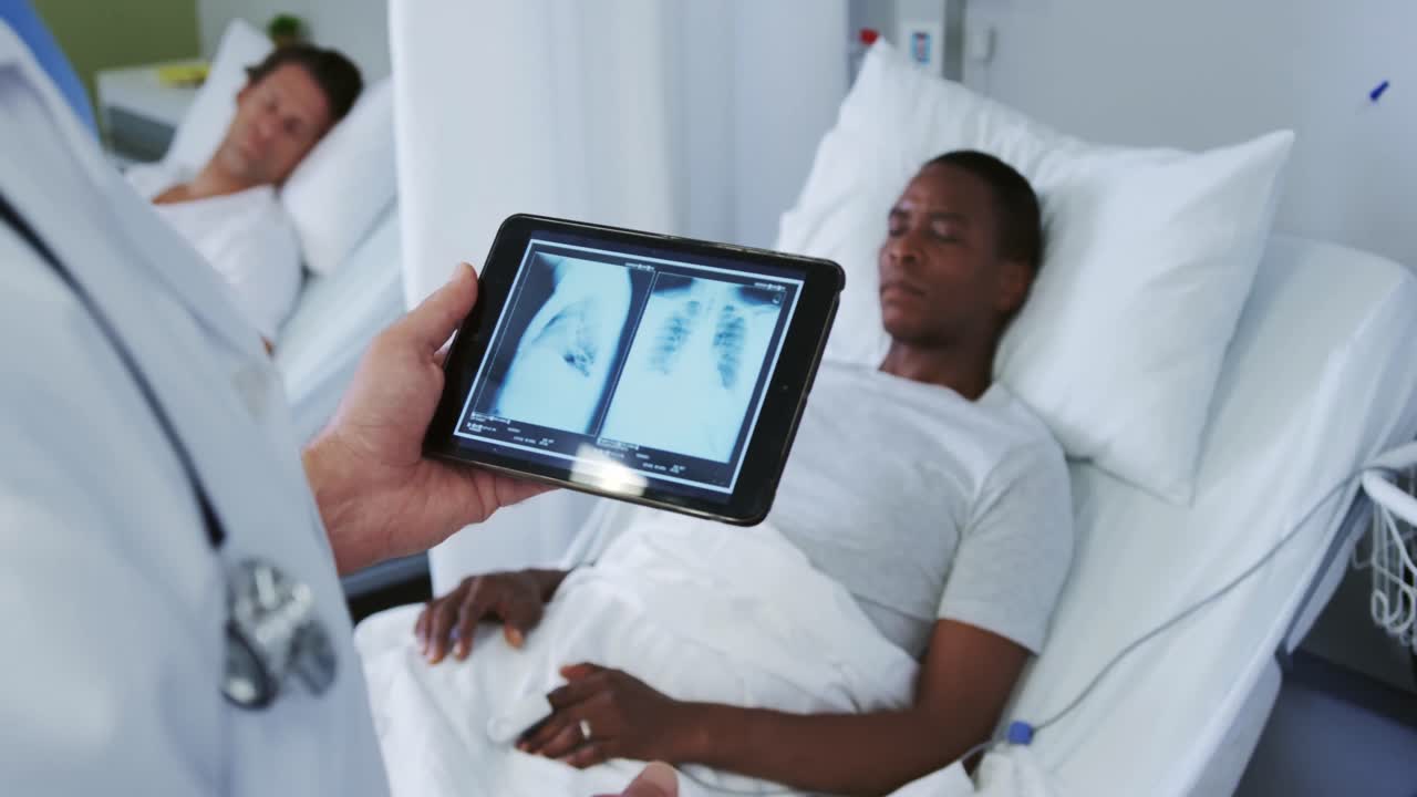 Close-up of Caucasian male doctor looking at x-ray report on digital tablet in the ward