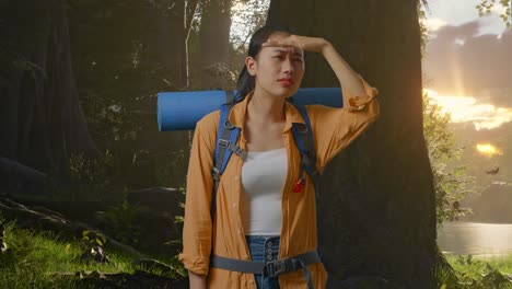 excursionista asiática con mochila de montaña mano frente sonriendo y mirando la distancia mientras explora la naturaleza del bosque