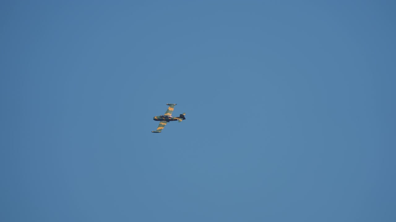 Gammelt militær jetfly med camouflage-maling flyver på blå himmel