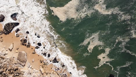 Bird-eye-aerial-of-sea-waves-crashing-into-a-majestic-natural-rock-formation-on-the-coastline