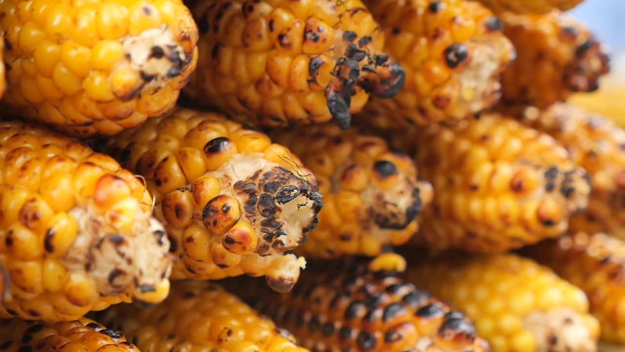 Zbliżenie na grillowaną kukurydzę w kolbie ułożoną w stos