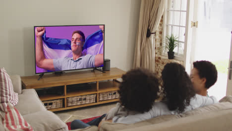 biracial family watching tv with caucasian male supporter with flag on screen
