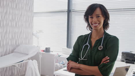 portrait of smiling female doctor with stethoscope standing in front of desk in office