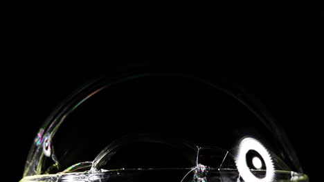 a soap bubble displays vibrant color reflections against a dark background, highlighting its delicate structure and dynamic surface