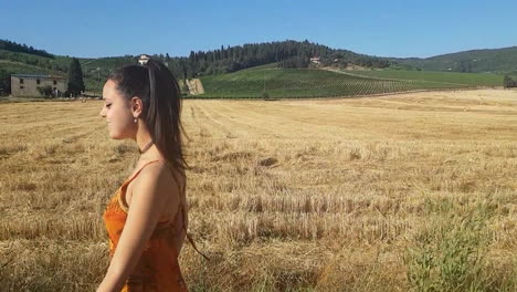 young brunette girl walking near a wheat field at the beginning of summer while singing