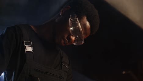 man wearing safety glasses in a dark industrial setting