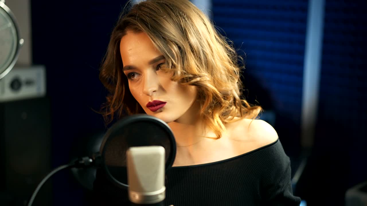 어린 소녀가 스튜디오에서 마이크로 노래하고 있습니다.