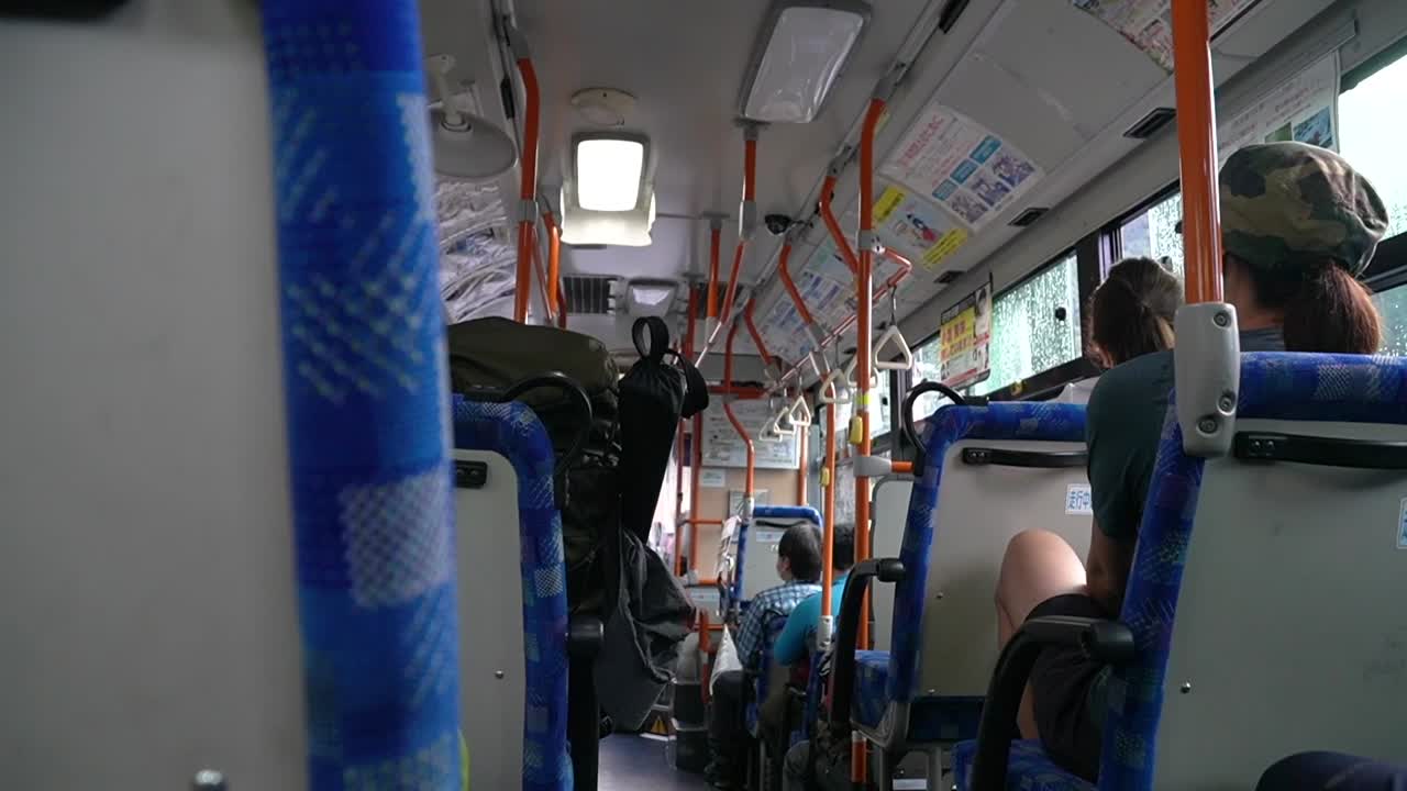 Back seat view of a public transport bus in Japan. People social distancing and wearing masks. Day time commute during covid 19.