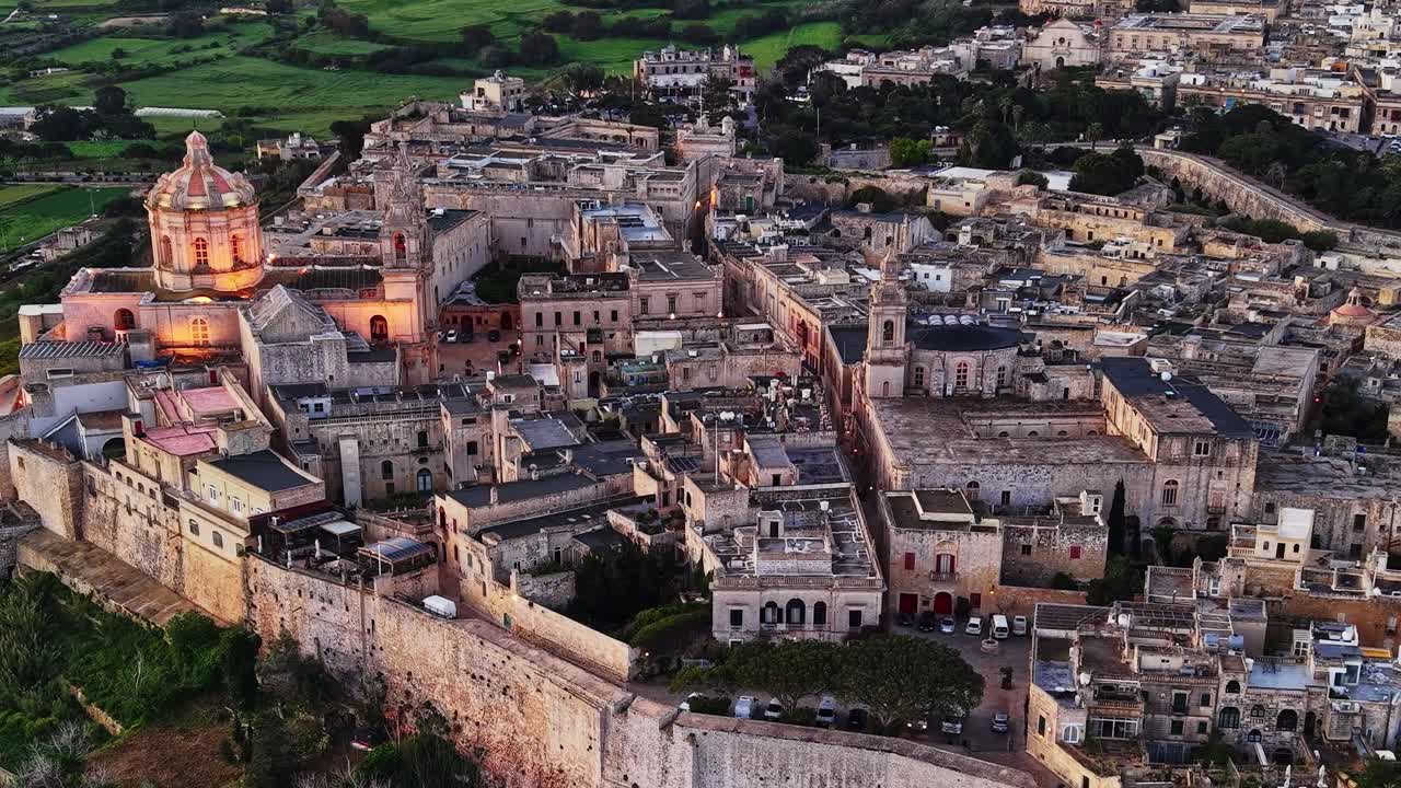 Vista de la histórica Mdina en Malta, con edificios antiguos y campos verdes