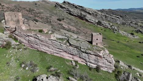 Lateral-aerial-drone-view-of-Zafra-Castle,-in-Guadalajara,-Spain,-built-in-the-top-of-a-rocky-hill