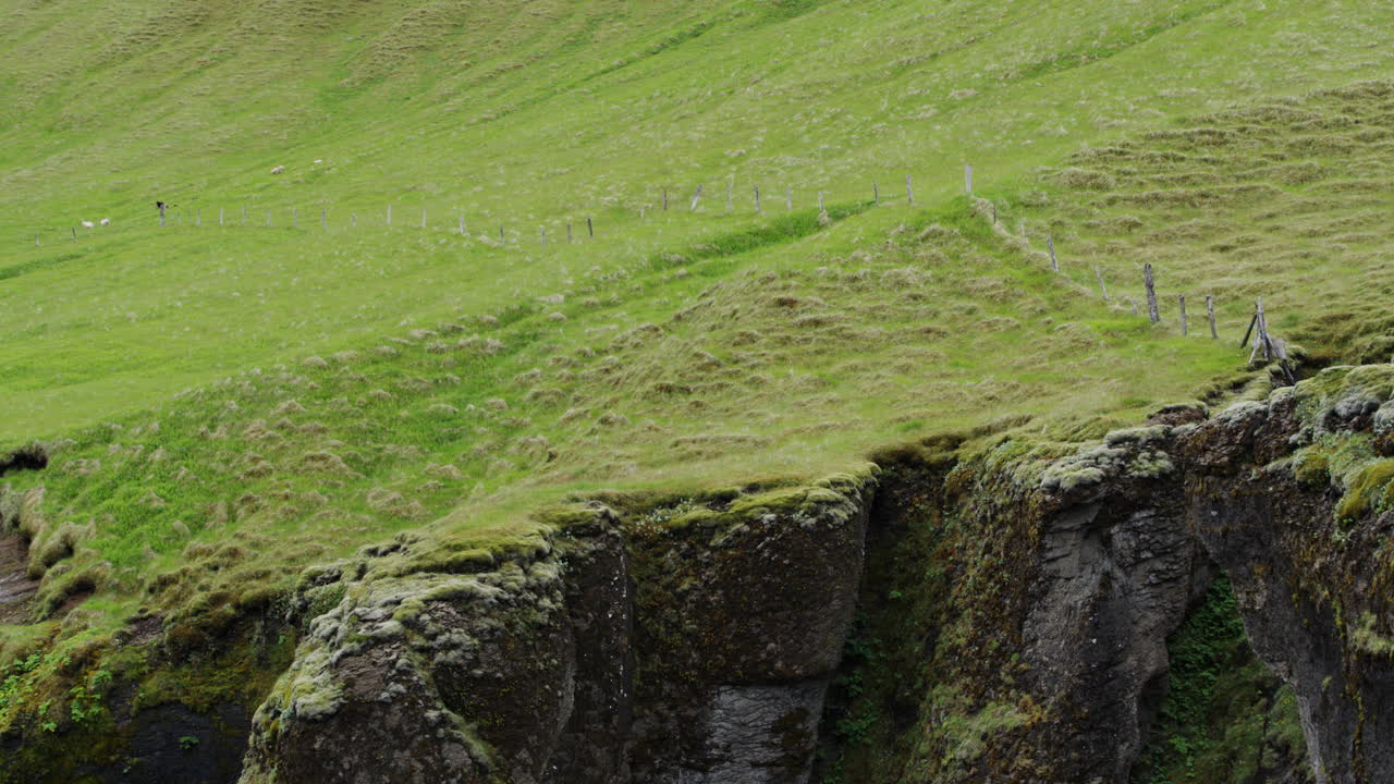 exuberantes pastos verdes conducen a una peligrosa caída sobre los bordes de los acantilados en fjadrargliufurs paisajes dramáticos en islandia