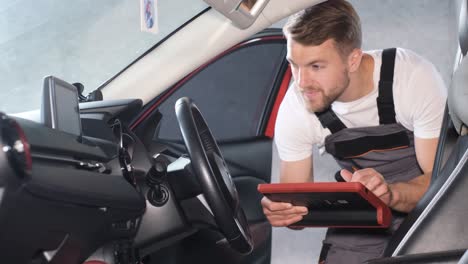 Car mechanic using diagnostic tool inside a car
