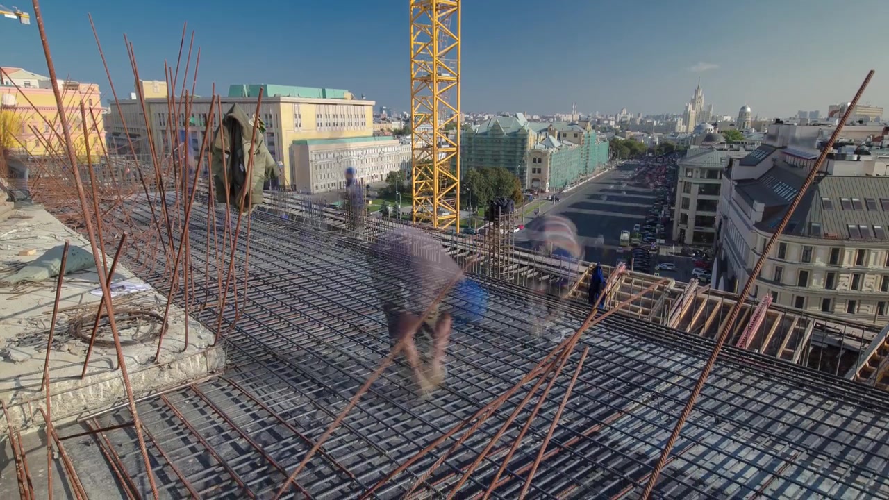 Construction workers working on steel rods used to reinforce concrete with scaffolding and tools of high rising building timelapse on a rooftop. Building under construction. Metal work in progress