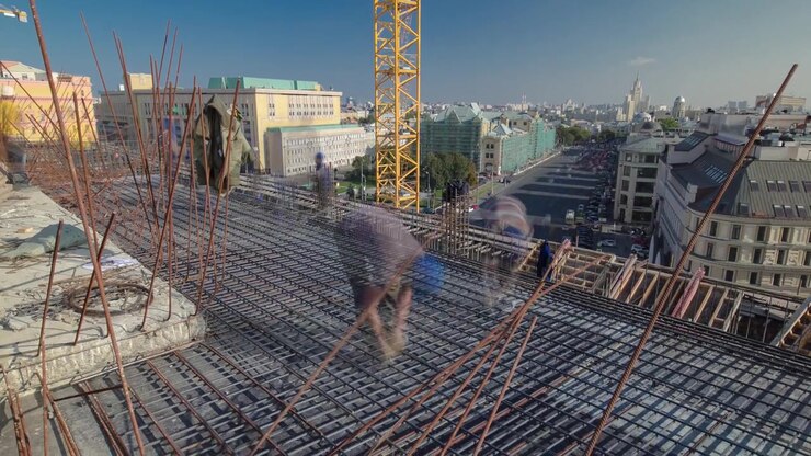 Bouwvakkers werken aan stalen staven die worden gebruikt om beton te wapenen, met steigers en gereedschap van een hoogbouw timelapse op een dak. Gebouw in aanbouw. Metaalwerk in uitvoering.