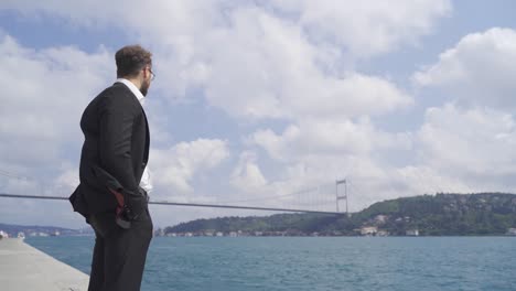 hombre de negocios reflexivo contra el mar por el estrecho en la ciudad.