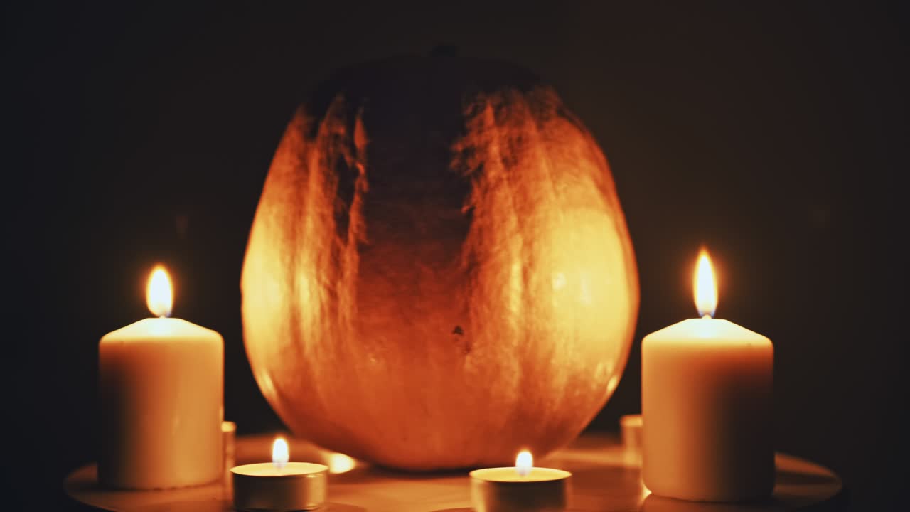 Rotation parallax effect Halloween pumpkin with burning candles around it glows amidst the darkness. Traditional Halloween symbol with bright lights. Emotions