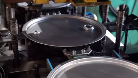 A conveyor system transports drum lids to a specialized punching machine