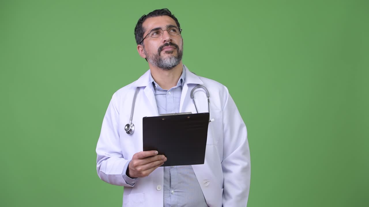Bello e barbuto medico persiano pensieroso mentre tiene in mano una cartella.